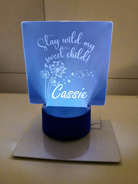 Personalized LED acrylic light with the text "Stay wild my sweet child!" and "Cassie", illuminated in a soft blue glow.