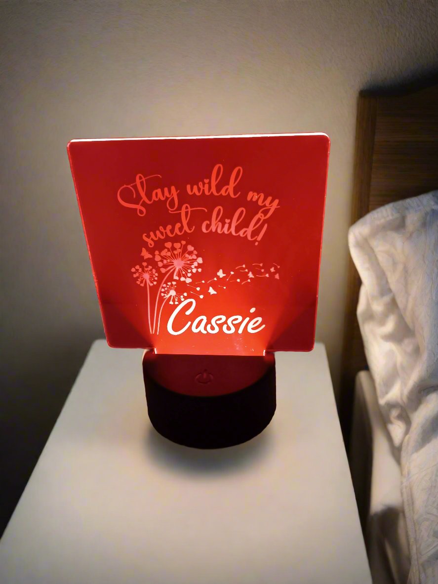 Personalized LED acrylic light on a bedside table, illuminated with the text "Stay wild my sweet child" and the name "Cassie."