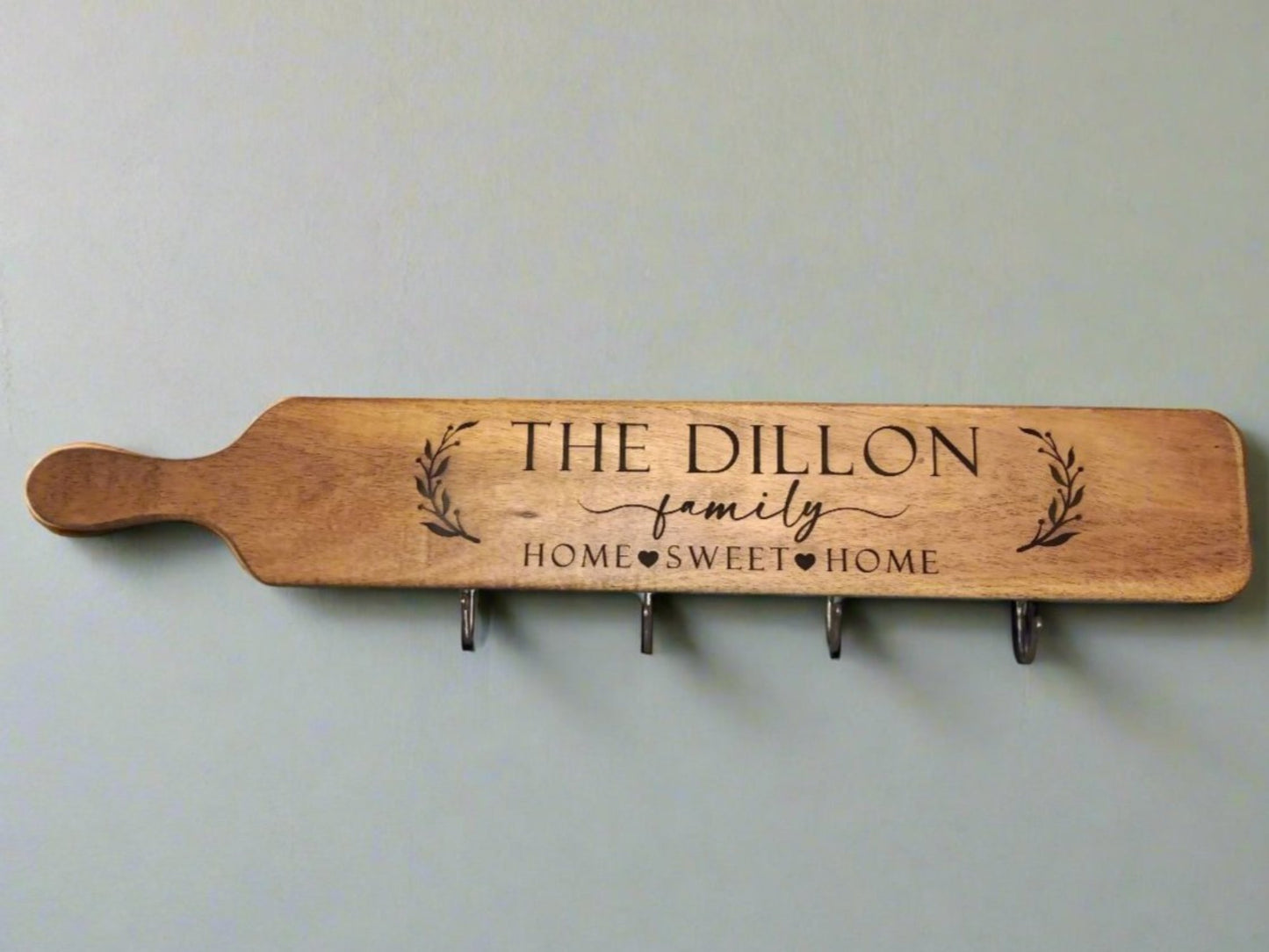 Wooden coffee mug holder with "The Dillon Family" and "Home Sweet Home" engraved, featuring four metal hooks for mugs.