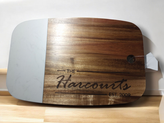 square cutting board with marble inlay and text "the harcourts" engraved on it