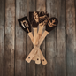 Handmade wood spoons with unique carved designs displayed on a rustic wooden background. Bundle of four tied together.