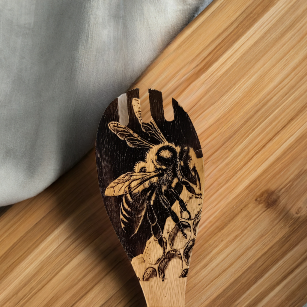 Handmade wooden spoon with detailed engraving of a bee on honeycomb, displayed on a wooden surface.